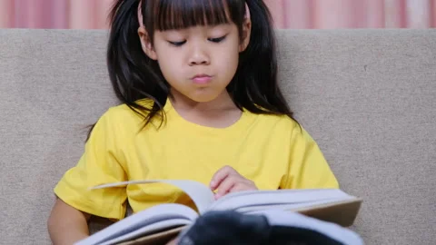 Cute little girl reading a book while si... | Stock Video | Pond5