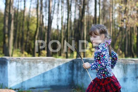 Cute little girl in red skirt runs in sunny green park with old fountain Stock Photos