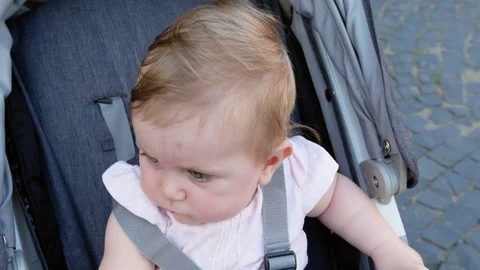A cute little girl is surprised. The child is sitting in a baby carriage. Stock Footage