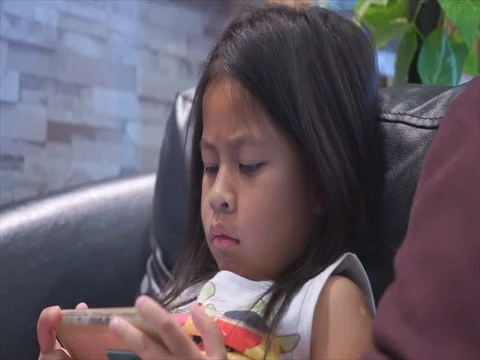 Cute little girl using mobile smartphone close up shot video in living room, 스톡 동영상 80596677