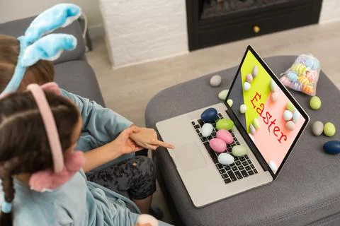 Cute little girls with bunny ears making a video call on a laptop. Stock Photos