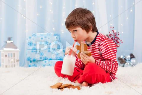 Cute little happy boy, eating cookies and drinking milk, waiting for Santa Stock Photos