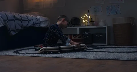 Cute little kid boy assembles radio controlled train in his room Stock Footage 105814674