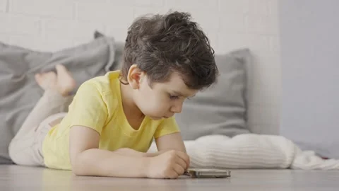 Cute little kid having fun using cellphone on the floor at home Stock Footage 245512060