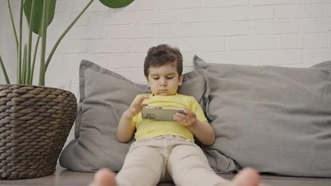 Cute little kid having fun using cellphone at home Stock Footage 245513883