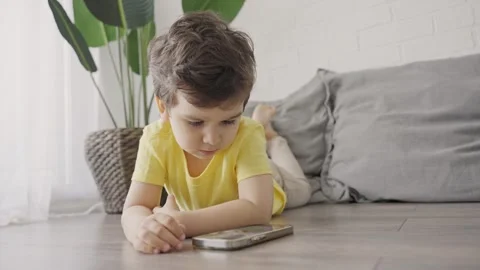 Cute little kid having fun using cellphone on the floor at home Stock Footage 247753423