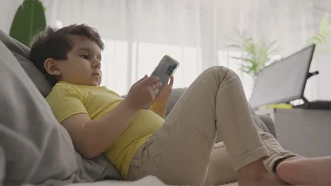Cute little kid lying on sofa enjoy using smartphone Stock Footage 245592464