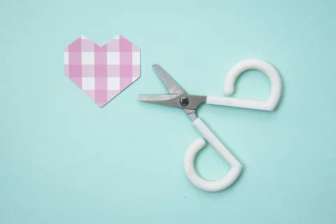 A cute little pair of scissors that try to cut hearts. Stock Photos