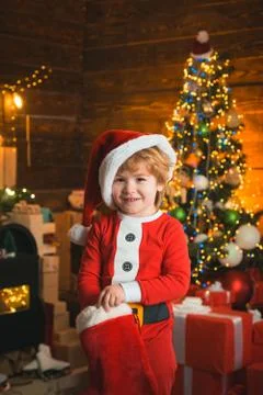Cute little santa baby with New years gifts on Christmassy background. Christmas Stock Photos
