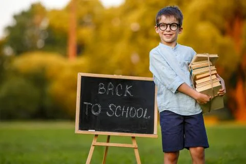 Cute little schoolboy carrying a stack of books Stock Photos