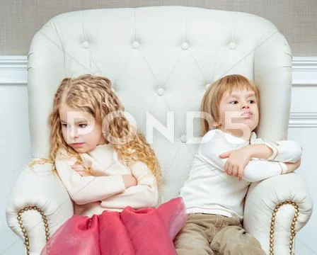 Cute little siblings (boy and girl) being at odds with each other, sitting Stock Photos