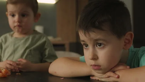 Cute little siblings sitting at table in kitchen watching cartoon video online Stock Footage 236950241
