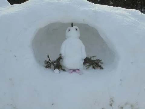 Cute little snowman inside of a hole in the snow. Stock Photos