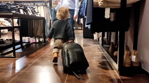 A cute little two-year-old child with a backpack goes shopping on his own Stock Footage 219091967