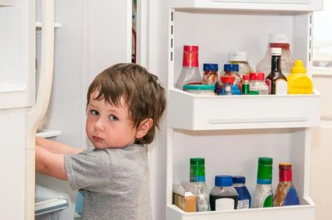 Cute llittle boy getting something to eat out of the refridgerator Stock Photos