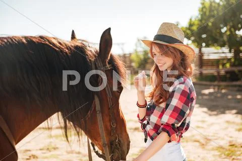 Cute lovely cowgirl taking care of her horse on ranch Stock Photos