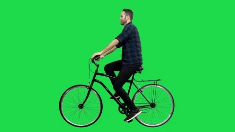 A Cute man riding a bicycle over a green screen, looking around and upwards. Stock Footage