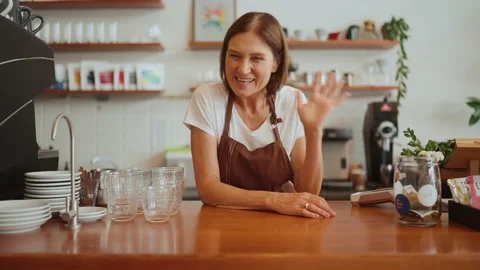 Cute mature barista looking at camera and greeting behind counter Stock Footage 238662848