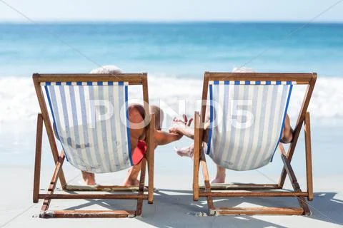 Cute mature couple lying on deckchairs Stock Photos