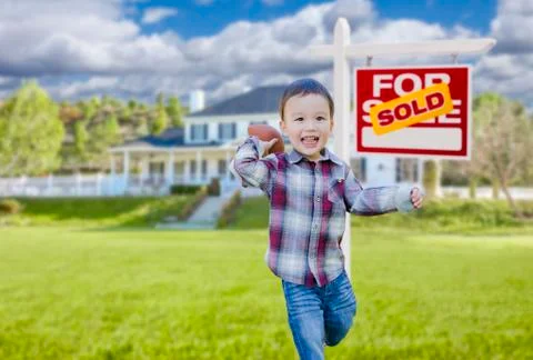 Cute Mixed Race Boy Playing Ball in Front Yard Near Sold Real Estate Sign. Stock Illustration
