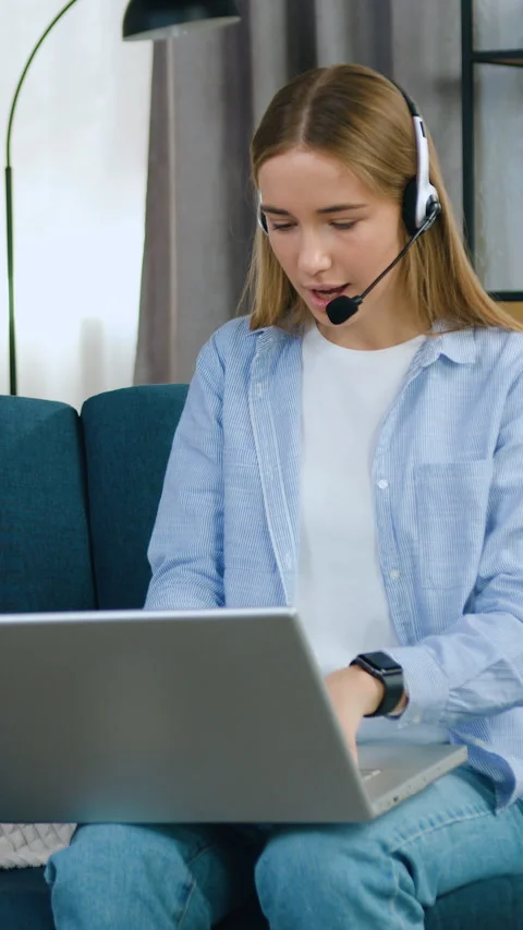 Cute modern purposeful 20-aged female student or freelancer in headset sitting o Stock Footage 331437782
