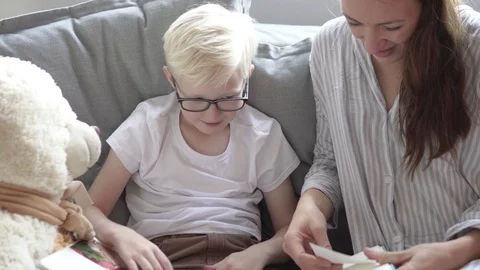 Cute mom and son insert photos into the boy is children's photo album Stock Footage 118519067