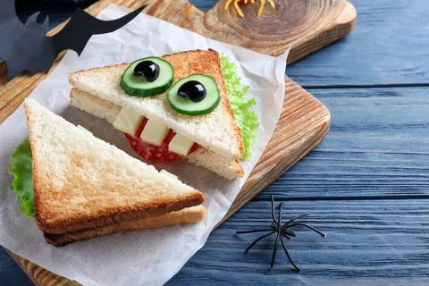 Cute monster sandwich served on blue wooden table, closeup. Halloween party f Stock Photos
