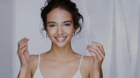 Cute mulatto girl touching her cheeks and wind blows hair behind Stock Footage 123732060
