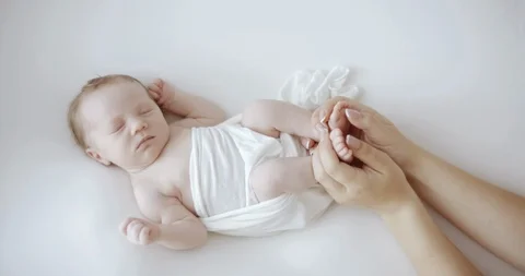 Cute newborn baby in white wrap sleeping on white blanket  while mother’s arms h Stock Footage 115041153