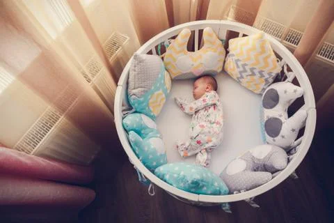 Cute newborn little girl sleeping in a white round crib Stock Photos