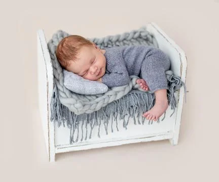 Cute newborn on tiny bed Stock Photos
