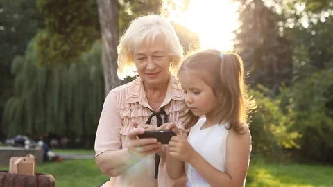 Cute old Slavic lady holding smartphone in hands, showing something to nice Stock Footage 97269449