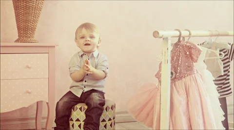 Cute one year old baby sitting on the ottoman in the nursery. Child claps. Video stock 67450067