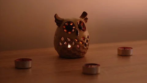 A cute owl candle holder, surrounded by small candles, turning on one by Stock Footage 95555791