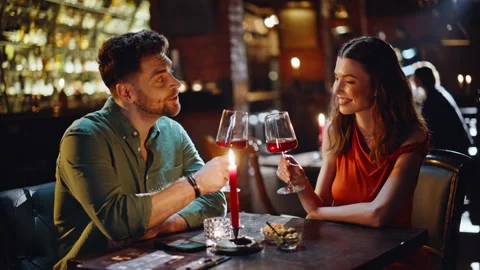 Cute pair drinking wine at romantic dinner in dark bar closeup. Smiling couple Vídeo Stock 334007843