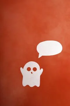 Cute paper ghost with emty text bubble in a white fog on an orange background Stock Photos
