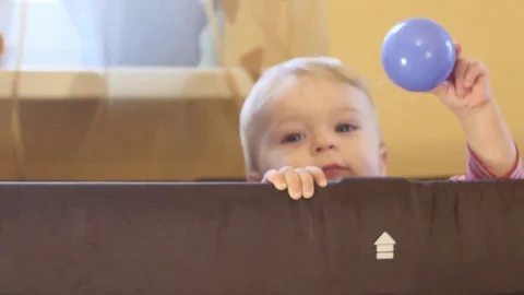 Cute playful 9 months old baby boy throws the ball Stock Footage 82299549