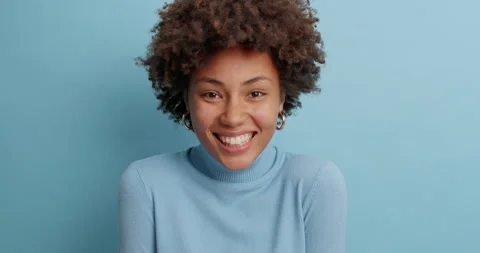 Cute positive dark skinned young woman with cheerful expression smiles gently Vidéo 142327208