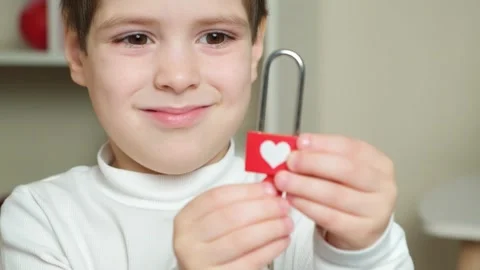 Cute preschool boy opens a red lock with heart keys. Children's Valentine's Day 스톡 동영상 240863052