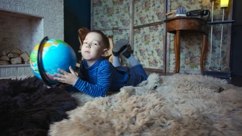 Cute preschool boy rotating globe lying on floor in children's room Stock Footage 76149235