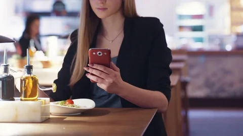 Cute pretty blonde in the black jacket is sitting in the café and smsing Video stock 74114136