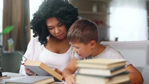 Cute primary school boy kid studying with his mother reading book Stock Footage 248690134