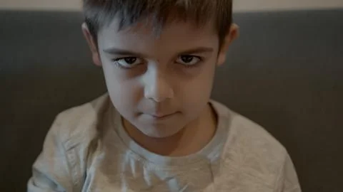 Cute primary school boy making angry face and smiling afterwards. Grumpy child Stock Photos