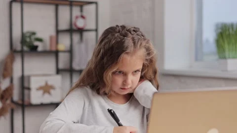 Cute primary school girl studying at home using laptop computer. Schoolgirl has Stock Footage 171615744
