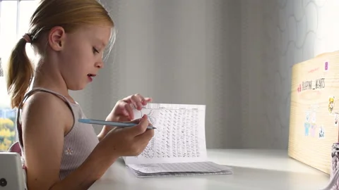 Cute primary schoolgirl learning writing doing homework sit at home table Stock Footage 220013145