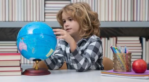 Cute pupil looking at globe in library at the elementary school. School child Stock Photos