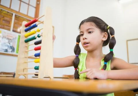 Cute pupil using abacus in classroom 写真素材