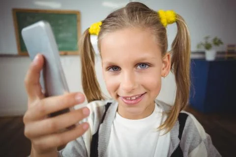 Cute pupil using smartphone in a classroom 스톡 사진