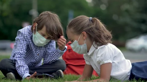 Cute pupils using smartphones at the elementary school. Boy and girl in safety Stock Footage 136099029