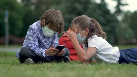 Cute pupils using smartphones at the elementary school. Boy and girl in safety Stock Footage 136262367